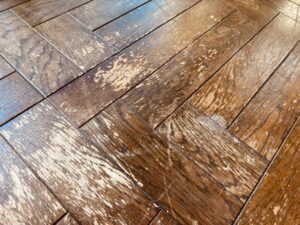 紫外線と経年劣化によりウレタン塗膜が白化し傷んだオークの複合フローリング表面