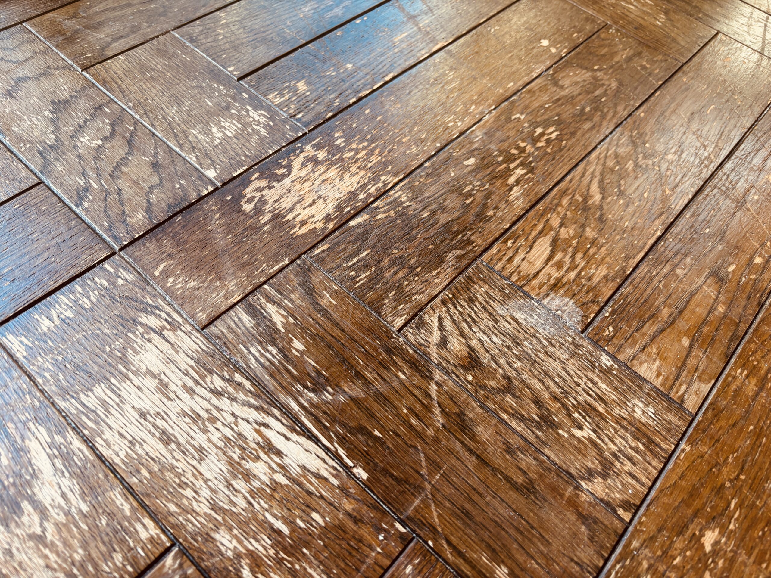 紫外線と経年劣化によりウレタン塗膜が白化し傷んだオークの複合フローリング表面