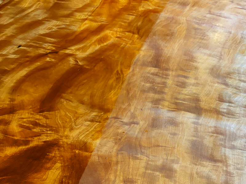 塗装済み（左）と未塗装（右）の栃の一枚板テーブルの比較。仕上げによって色味と杢目の立体感が変化している様子。