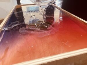 制作途中のレジンテーブルに透明なレジンをゆっくり流し込んでいる様子のクローズアップ