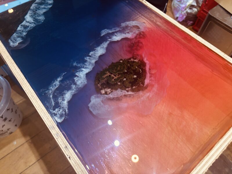 青から赤へとグラデーションするレジンの中に小さな島を配置した、制作途中のレジンテーブル俯瞰写真
