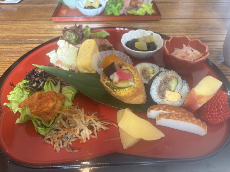 お正月らしい前菜と巻き寿司、稲荷寿司、黒豆や数の子が盛り付けられた山麓カフェのランチプレート