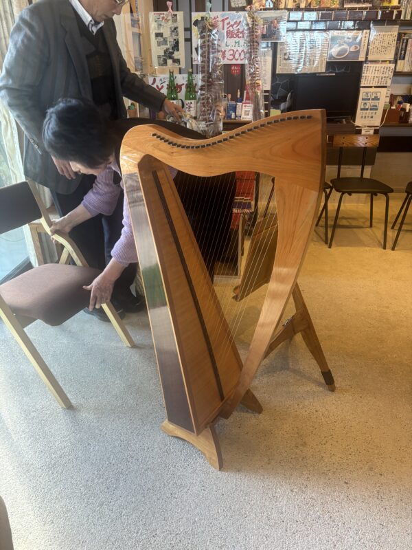 店内で演奏準備が進められる、木製フレームが美しい大和ハープと調整を行う演奏者