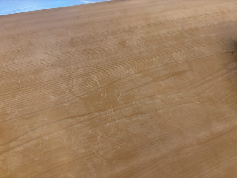 ヒノキのカウンターをムクリペで研磨中。長年の使用による細かな傷や白化した表面が見える状態