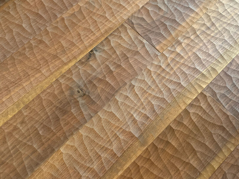 ブラックウォルナット無垢フローリングのアローカット加工。矢羽根状の彫りが光を受けて際立つ床面