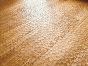 アッシュ（タモ）無垢フローリングのスプーンカット加工。シャープな木目と細かな彫り跡がリズムを生む床面