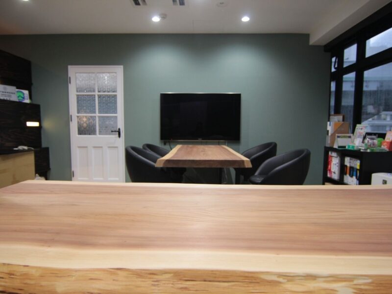 壁掛けモニター前に設置された一枚板テーブル。会議用途に合わせてサイズと厚みを調整した無垢天板。