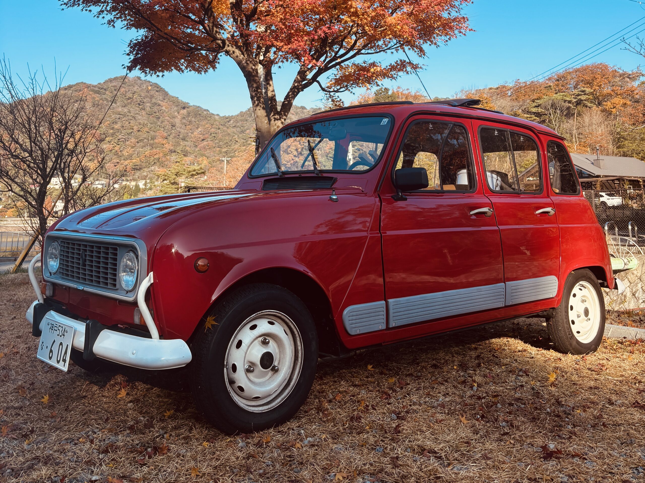 紅葉した山を背景に停車する赤いルノー4GTLの外観写真