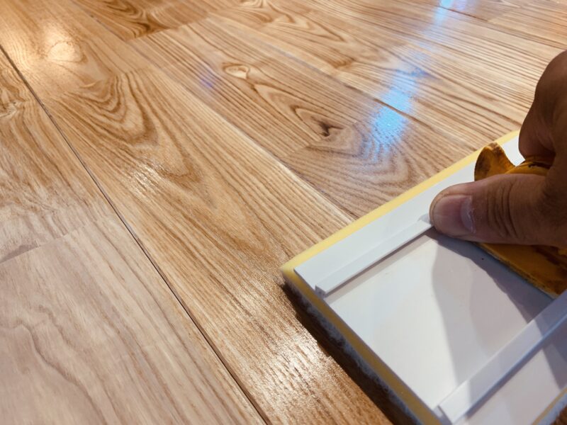 オスモ塗装を均一に伸ばす施工風景。アッシュ材の木目が濃くなる様子。