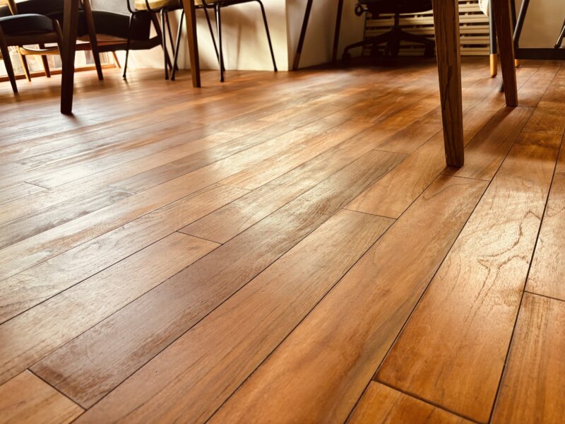 家具のある室内で再生後のインドネシアチーク無垢フローリングが自然光を受けている様子